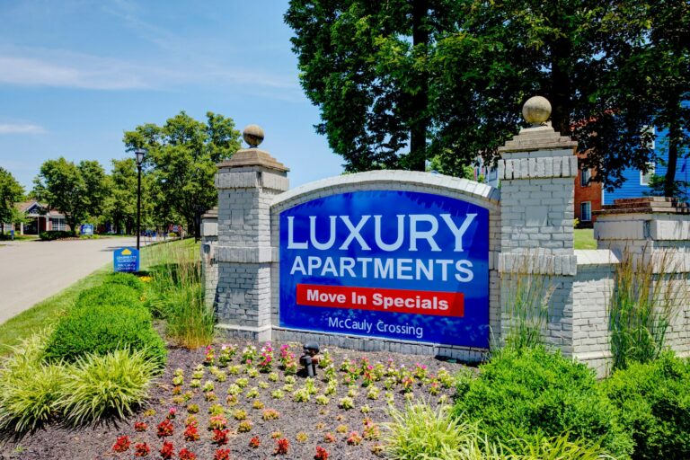 The front entrance sign with beautiful landscape at McCauly Crossing Blue Ash apartments.